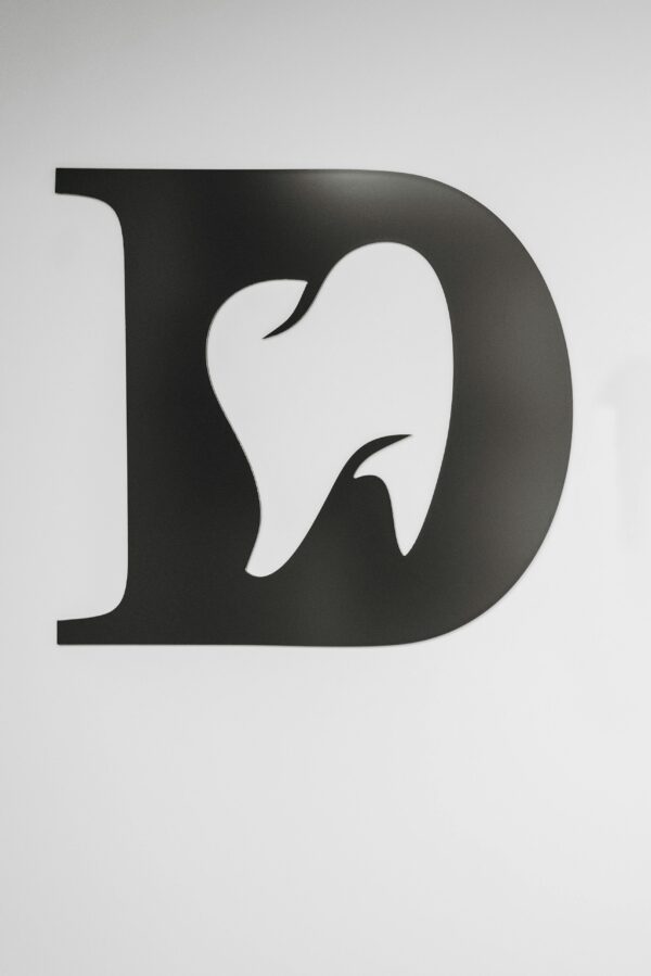 Home Simple black and white tooth design within letter D, ideal for dental branding.