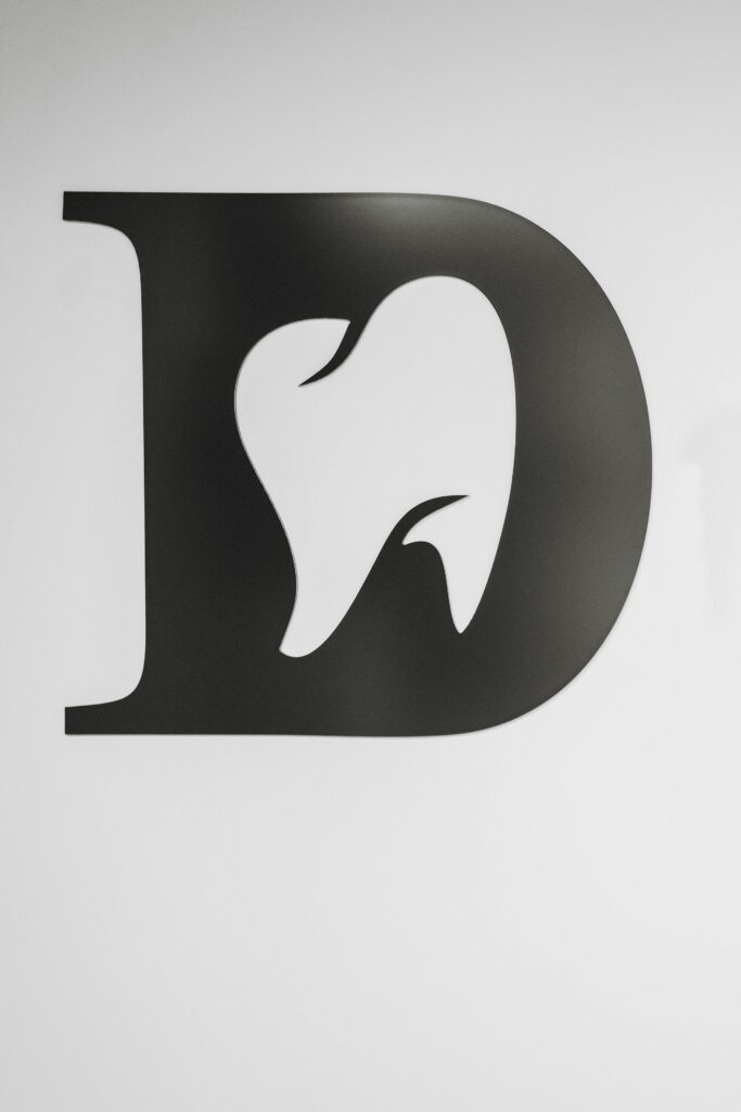 Home Simple black and white tooth design within letter D, ideal for dental branding.